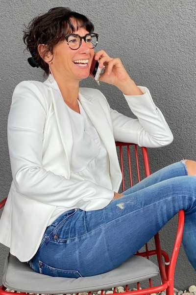 Claudia Potschigmann beim Selbstbewusstsein stärken Online Kurs mit Handy beim Telefonieren auf einem Stuhl sitzend